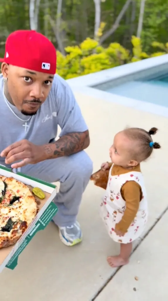 Jamal Morton and his daughter, Rose, next to a pizza box by a swimming pool.