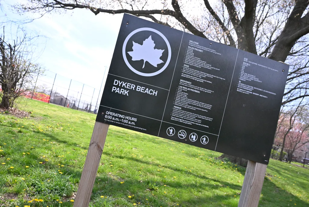 A park sign with rules and operating hours for Dyker Beach Park.