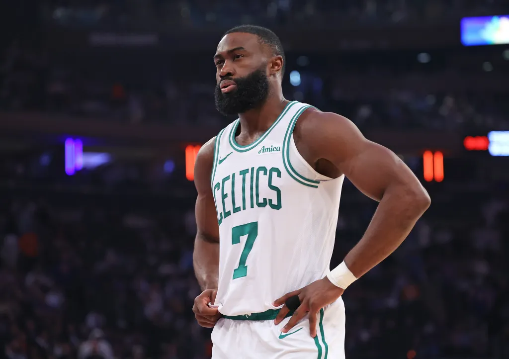 Jaylen Brown of the Boston Celtics wearing a white jersey with green trim and the number 7, hands on hips, looking intently to the left.