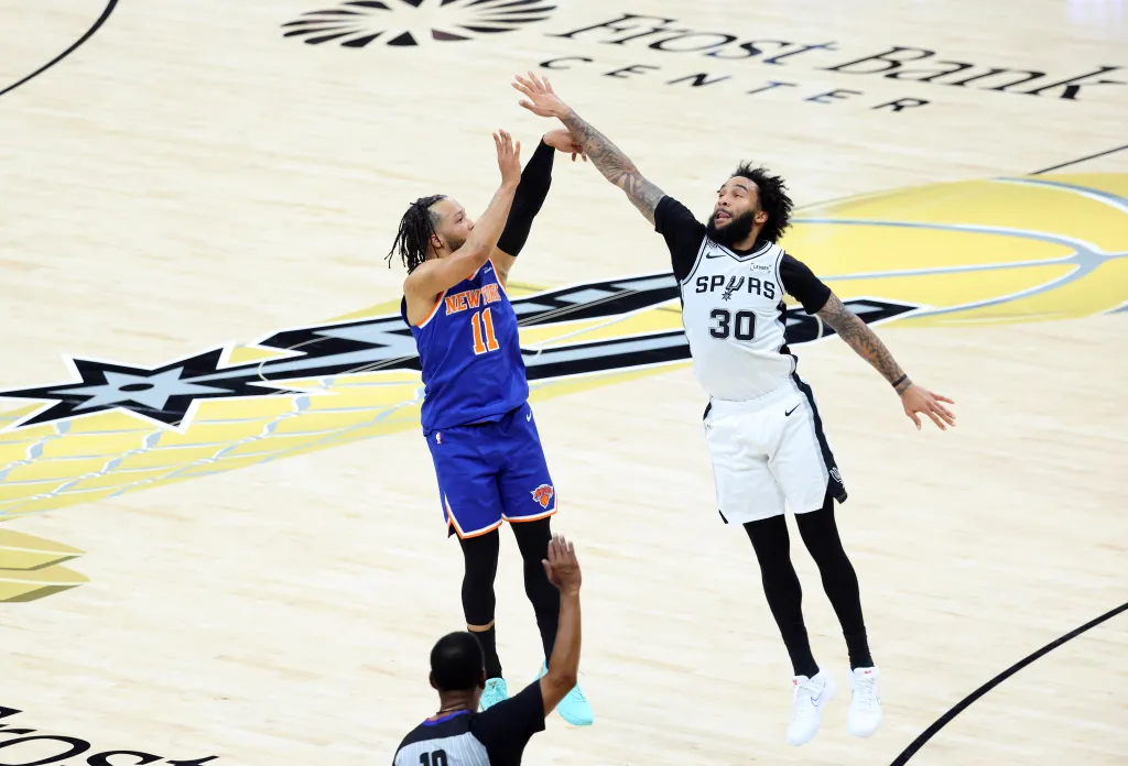 New York Knicks guard Jalen Brunson #11 hits a three-point shot over San Antonio Spurs forward Julian Champagnie #30 during the 1st half.