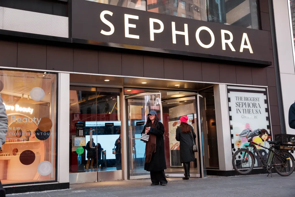 Exterior of a Sephora store in Times Square, New York, with a woman entering and another standing outside.