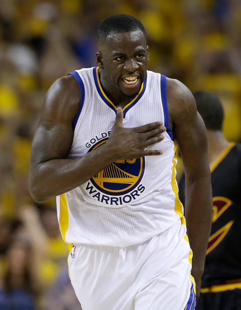 Draymond Green in his Warriors jersey, with a hand over his chest.
