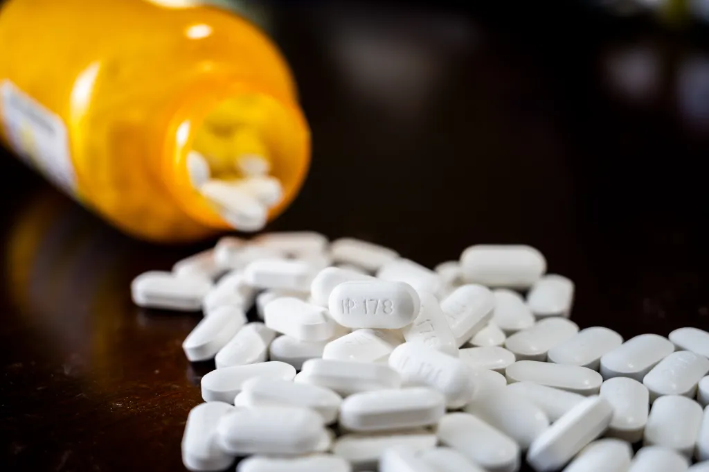 White pills spilling from a yellow bottle onto a dark surface.