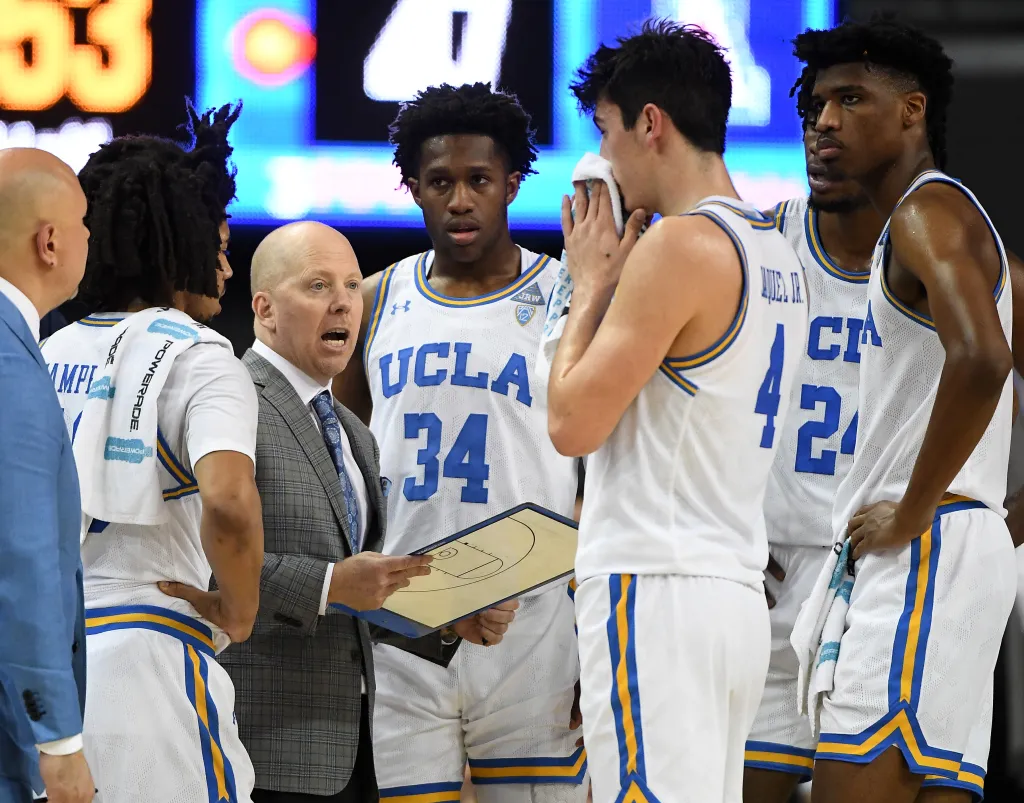 UCLA basketball coach Mick Cronin with his team during a timeout.