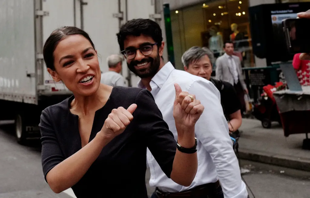 Alexandria Ocasio-Cortez and Saikat Chakrabarti giving thumbs up to supporters.