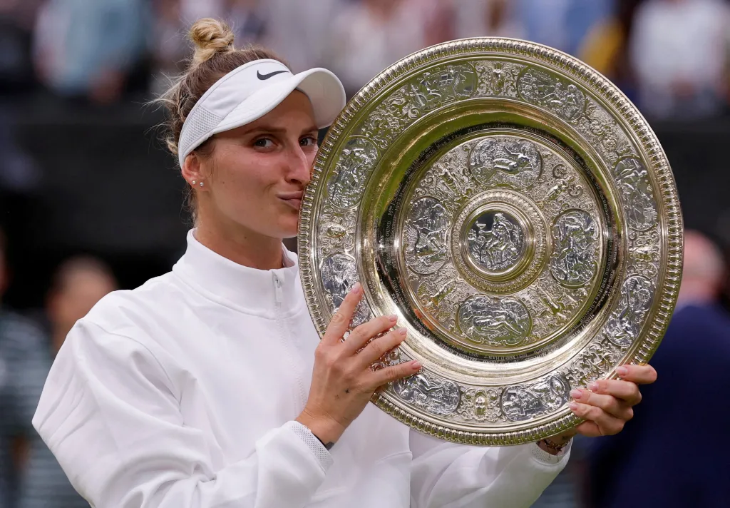 Markéta Vondroušová kisses the Wimbledon trophy.