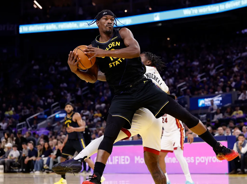 Jimmy Butler of the Miami Heat in a Golden State Warriors jersey driving to the basket with the basketball.