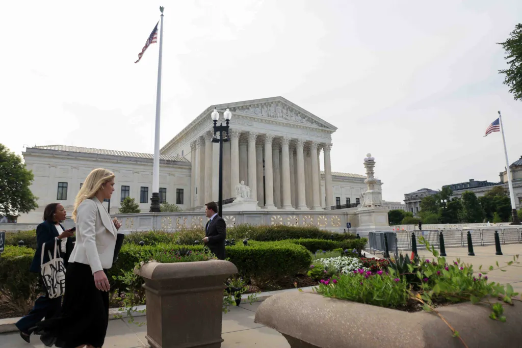 The US Supreme Court building on a decision day with people walking by.