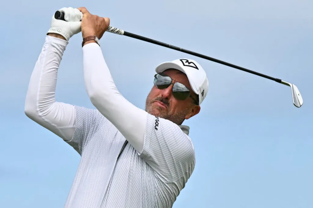 Golfer Phil Mickelson watches his iron shot.