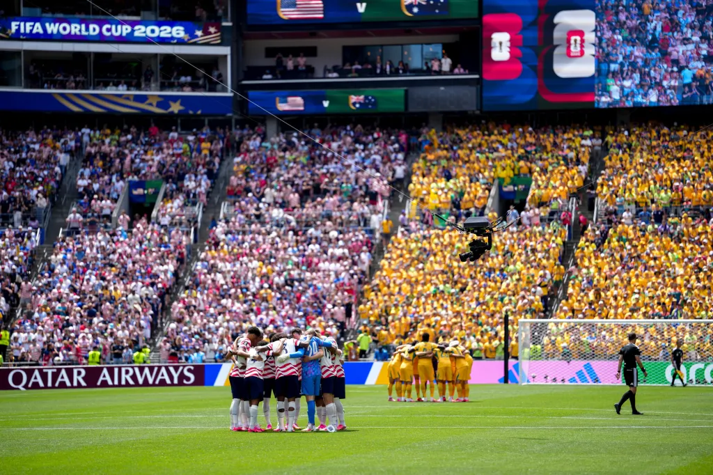The US and Australian soccer teams huddle on the field during a 2026 FIFA World Cup Group D match.