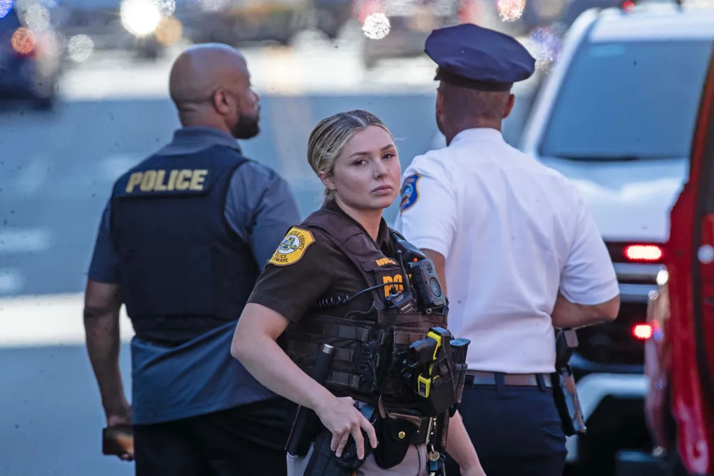A female police officer with tactical gear and a male officer in a white uniform stand outside ChristianaCare Wilmington Hospital.
