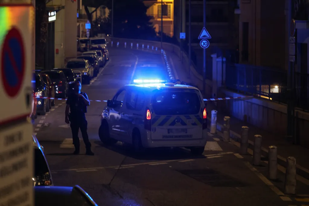 A police officer guarding a street in Monaco with a police car after an explosion.