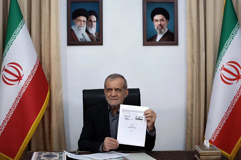 Iranian President Masoud Pezeshkian holding up a signed memorandum of understanding.