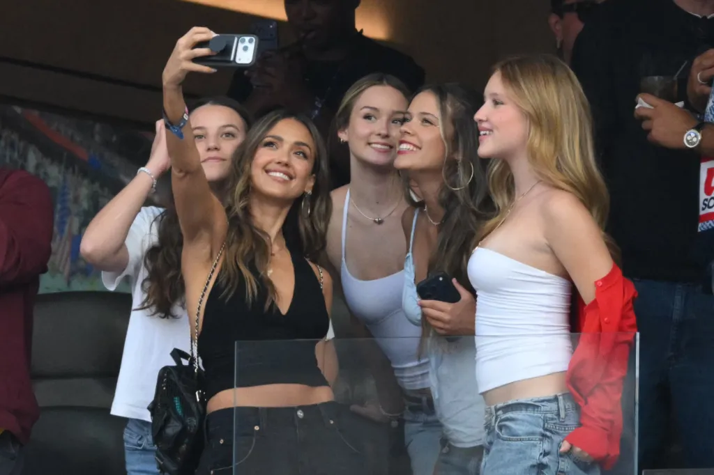 Actress Jessica Alba taking a selfie with others at the 2026 World Cup Group D football match.