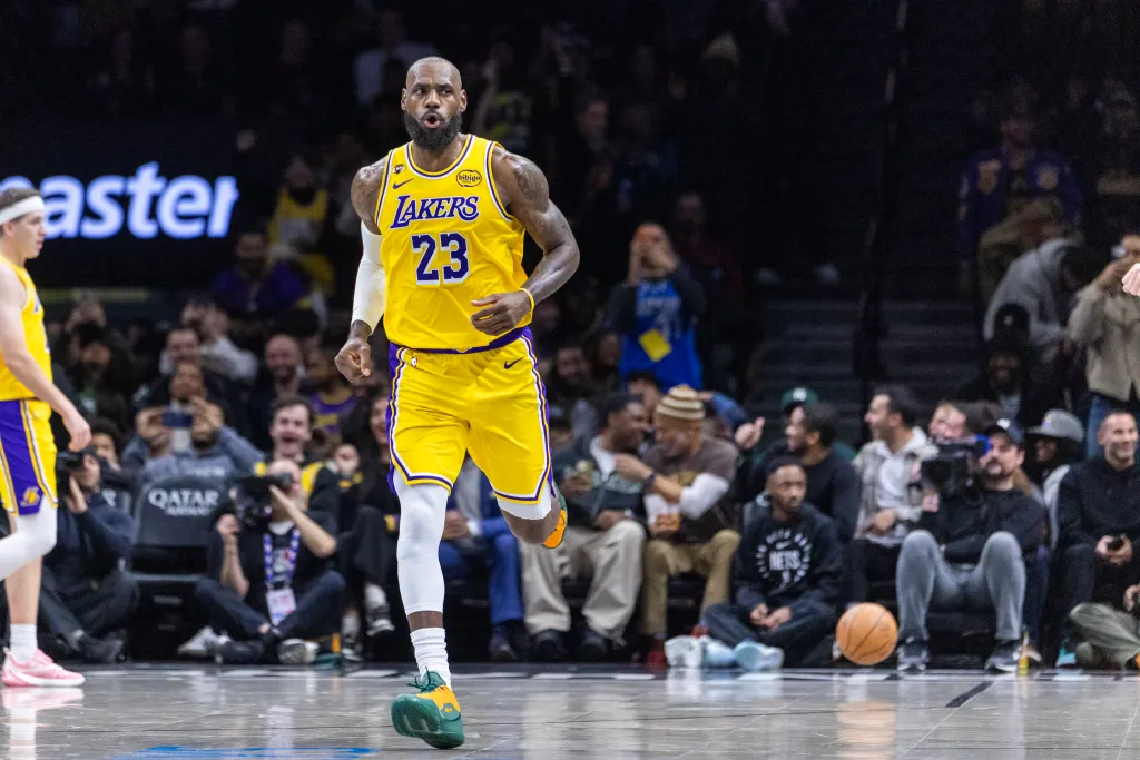 LeBron James wearing a yellow Los Angeles Lakers jersey with "23" on it, running on a basketball court.