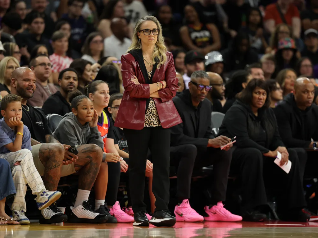 Las Vegas Aces head coach Becky Hammon in a red leather jacket on the sidelines.