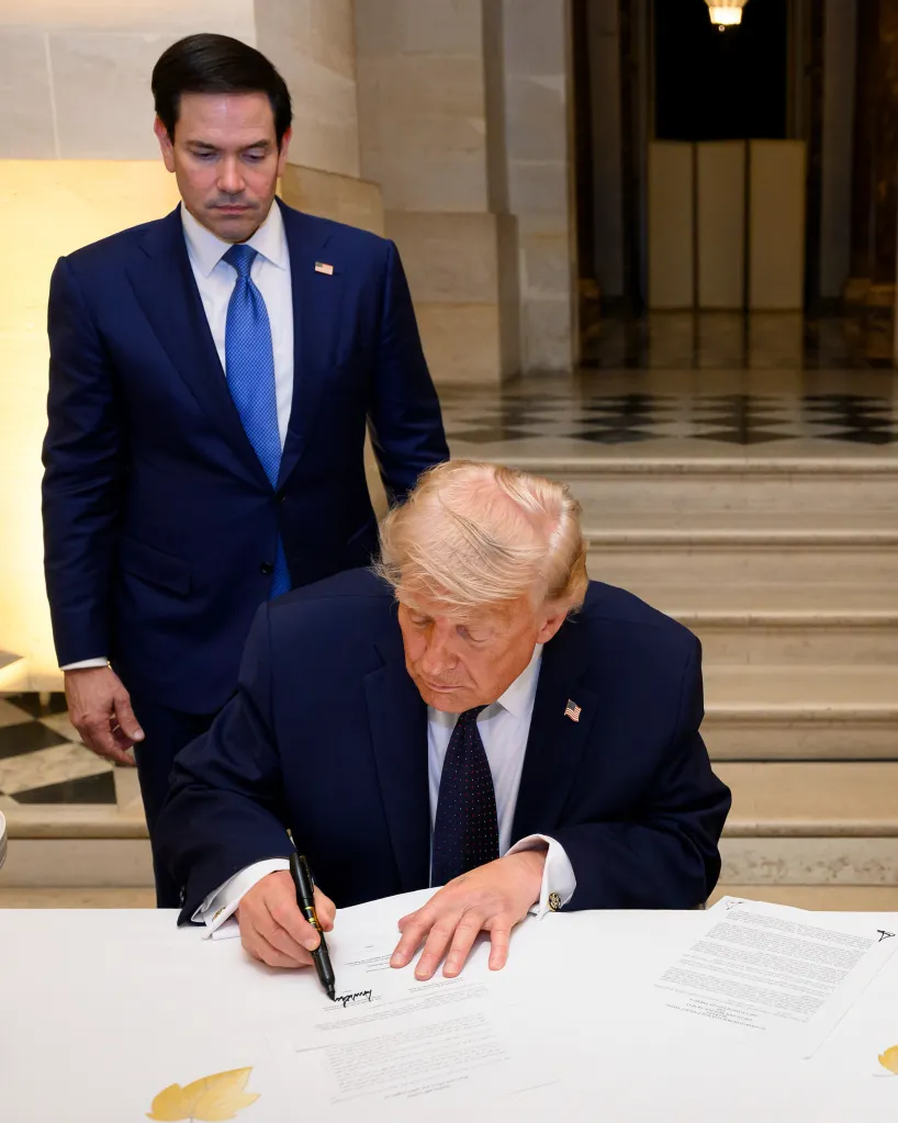 President Donald Trump, right, signs a Memorandum of Understanding between the Islamic Republic of Iran and the United States as Secretary of State Marco Rubio, left, look on at the Palace of Versailles June 17, 2026, in Versailles, France.
