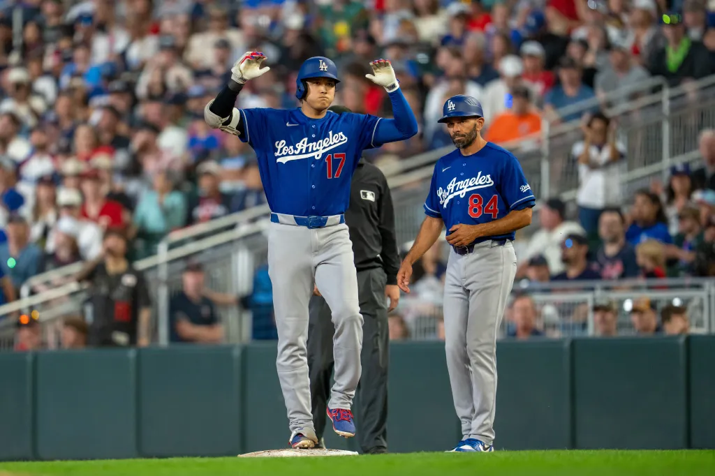 Los Angeles Dodgers player Shohei Ohtani celebrates a home run as coach Dino Ebel watches.