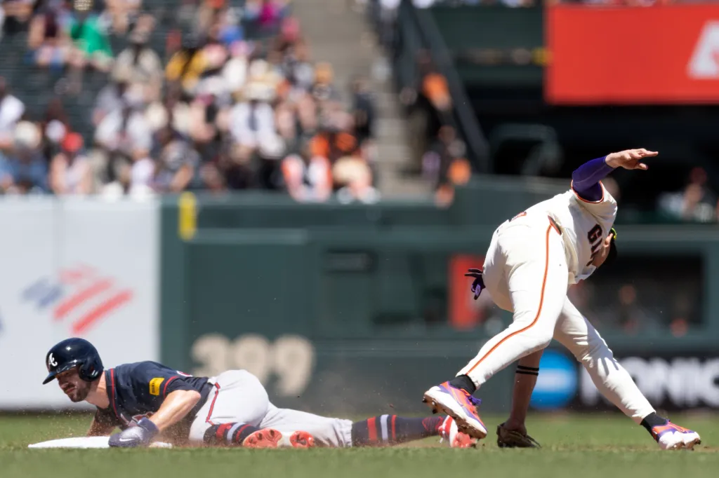 A San Francisco Giants player attempts to tag an Atlanta Braves player sliding into base.