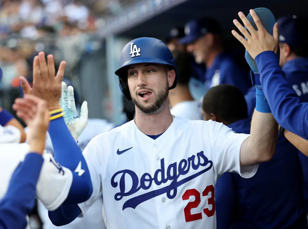 A Los Angeles Dodgers player high-fiving teammates in the dugout.