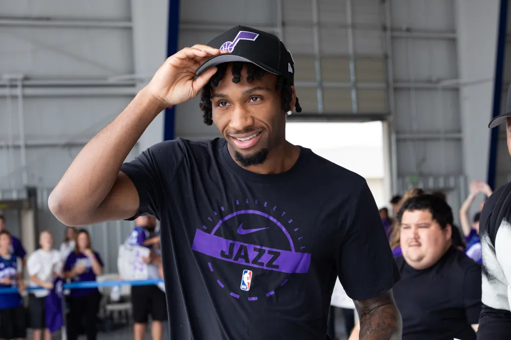 Darryn Peterson adjusting his Utah Jazz hat and smiling.
