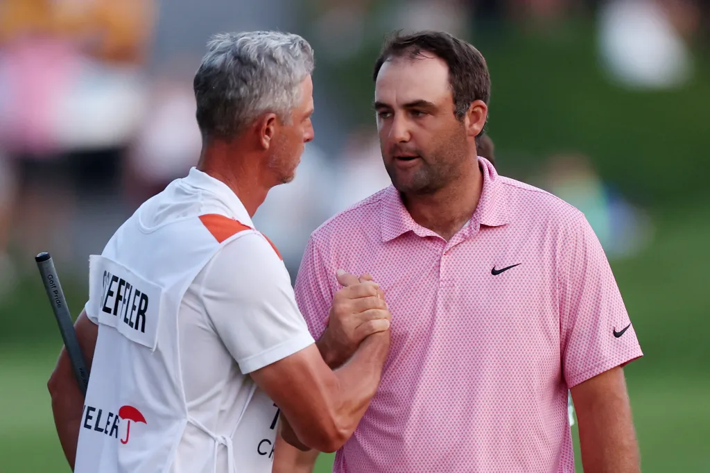 Two golfers shake hands on the green.