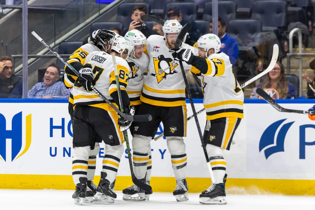 Pittsburgh Penguins players celebrating a goal on the ice.