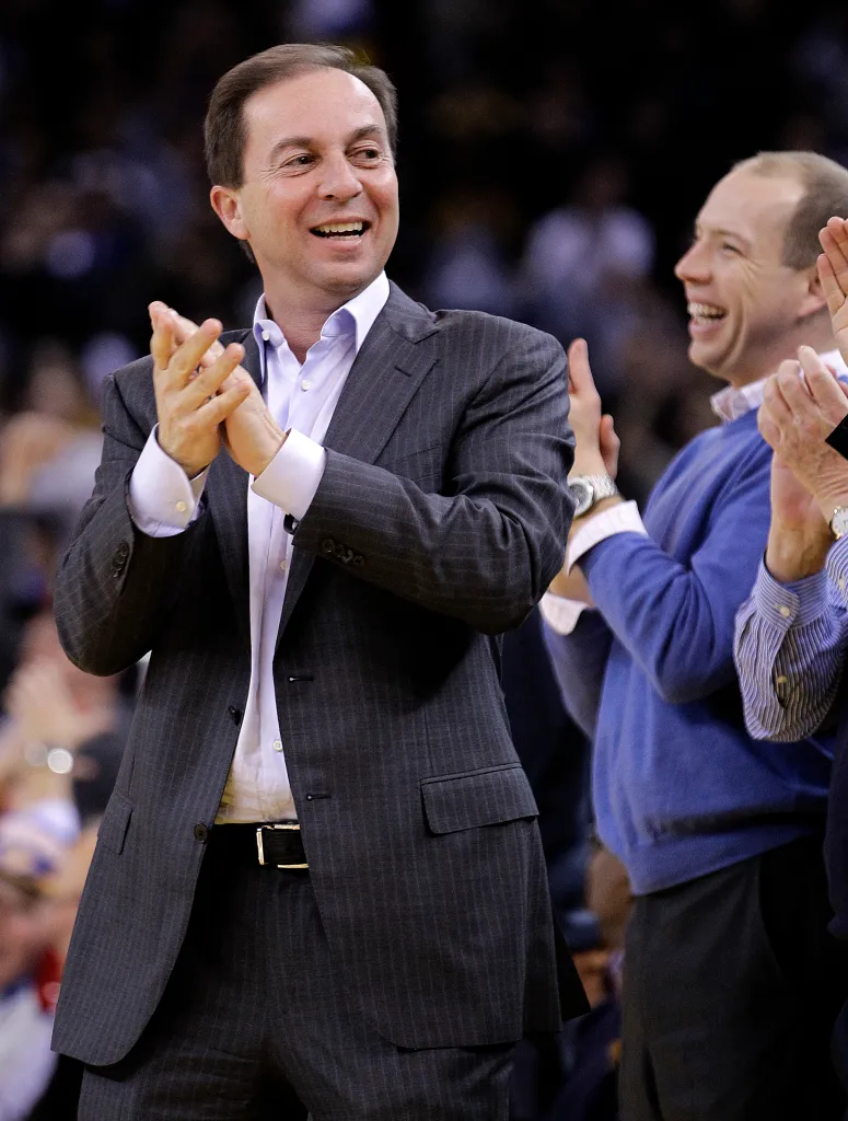 Warriors owner Joe Lacob clapping and smiling, with general manager Mike Dunleavy Jr. laughing next to him.