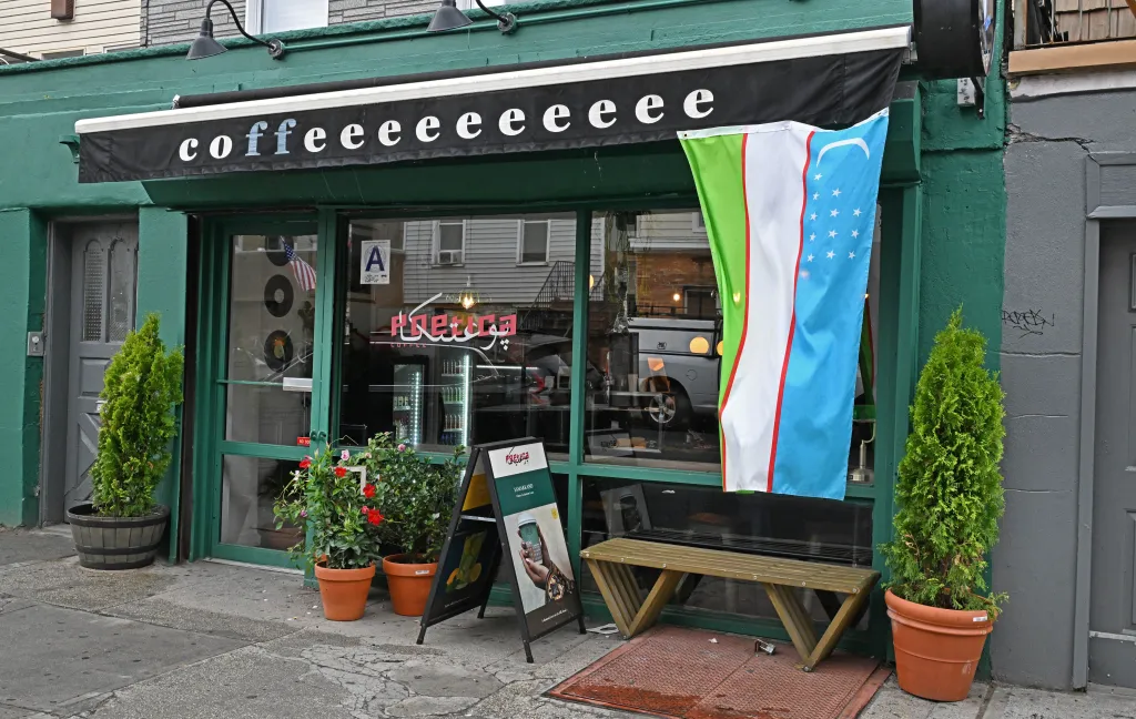 Exterior of Poetica Coffee shop with an awning that reads "coffeeeeeee" and a flag from Uzbekistan hanging by the door.