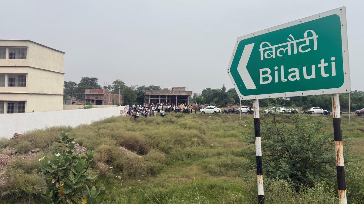 Nameplate of Bilauti village seen on Ara-Buxar NH in Bhojpur district of Bihar, as crowd gathers in  the backdrop at the house of Bharat Bhushan Tiwari.