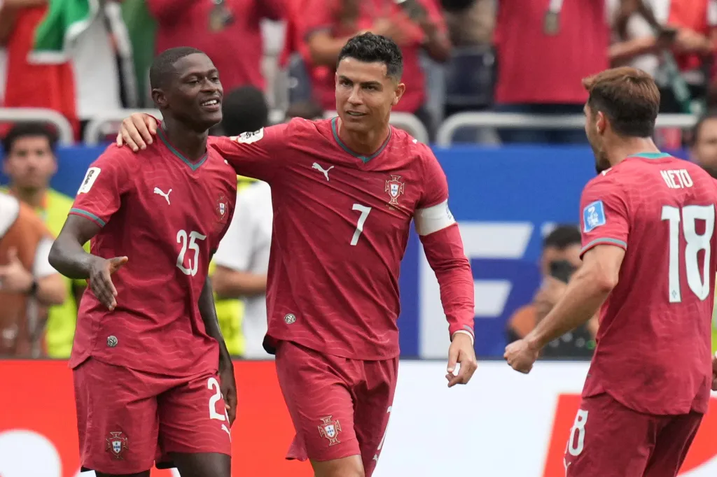 Portugal's Nuno Mendes (25) celebrates with Cristiano Ronaldo (7) after scoring his side's second goal during a World Cup match.