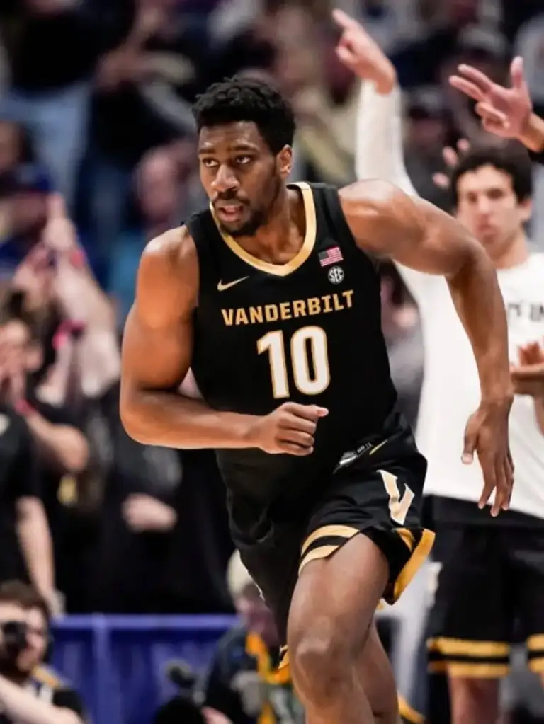 A male Vanderbilt basketball player in a black and gold jersey with number 10, running on the court.