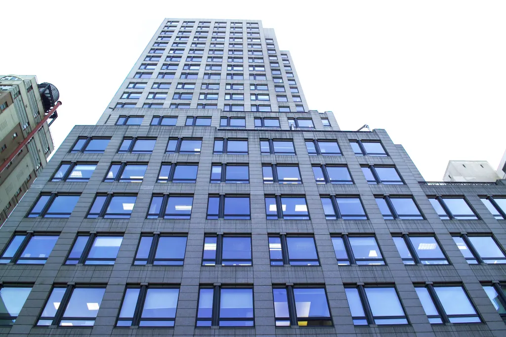 A low-angle view of 667 Madison Avenue & 61st Street, a tall building with many reflective windows.