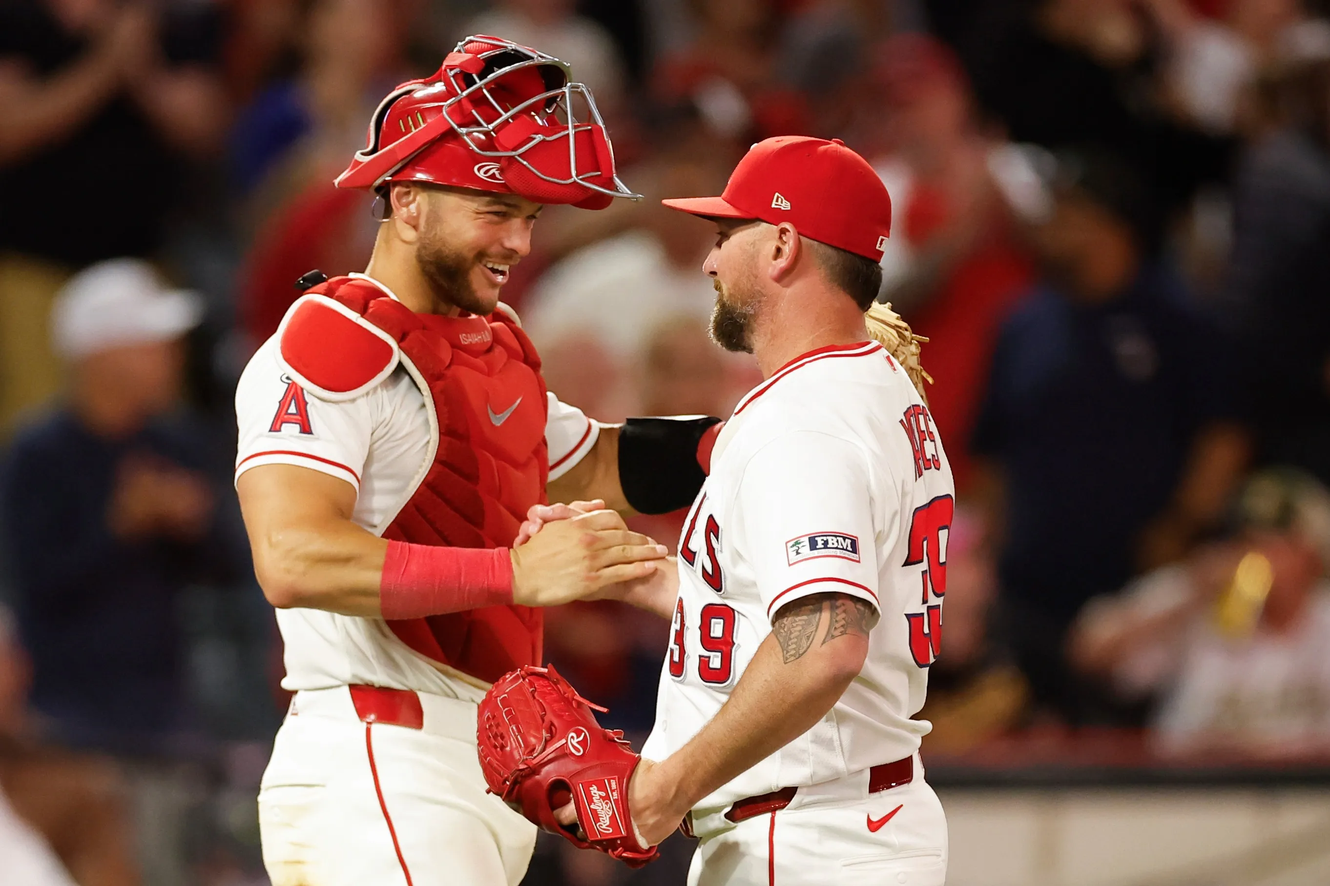 Two baseball players, a catcher and a pitcher, high-five on the field.