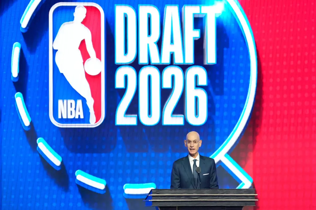 Adam Silver speaking at a podium in front of a blue screen with the NBA logo and "DRAFT 2026" displayed.