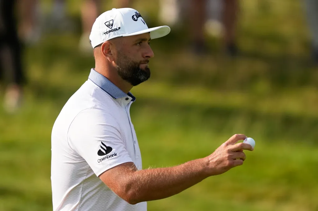 Jon Rahm holding a golf ball.