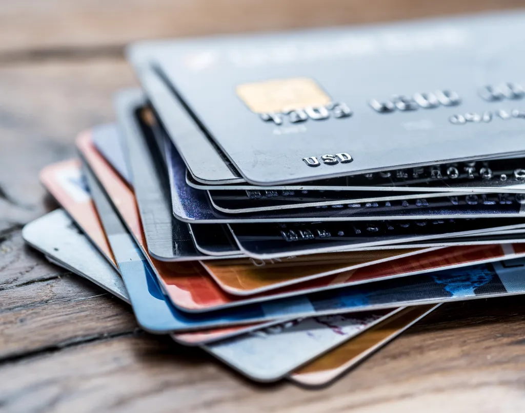 Stack of various credit cards on a wooden surface.