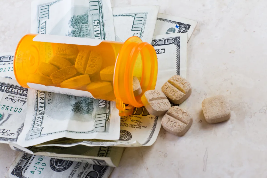 prescription jar spilled on the counter with american bills