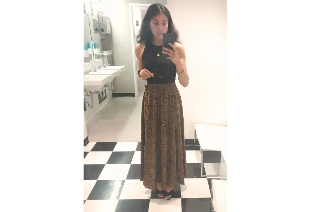 A woman wearing a leopard skirt, taking a selfie.