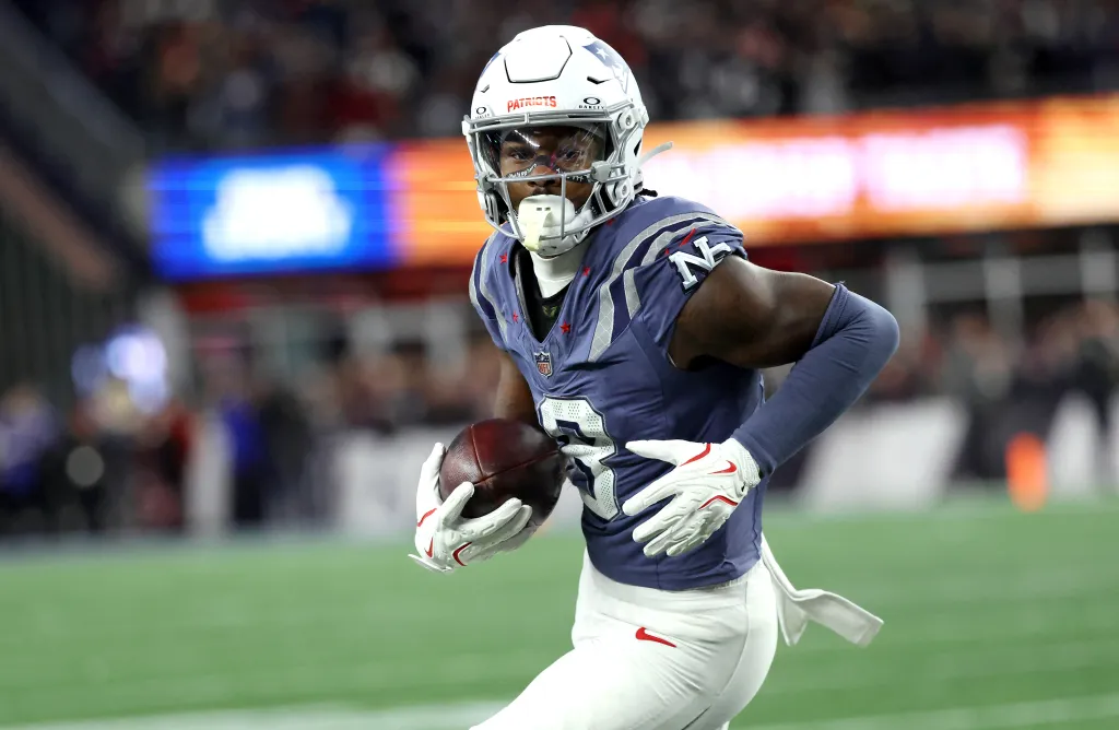A New England Patriots player in uniform running with the football during a game against the New York Jets at Gillette Stadium.