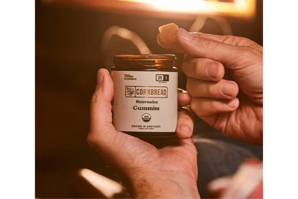 A hand holding a bottle of Cornbread Hemp.