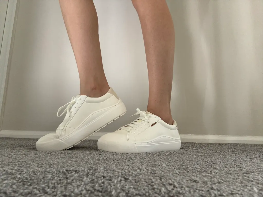 A woman wearing white sneakers.