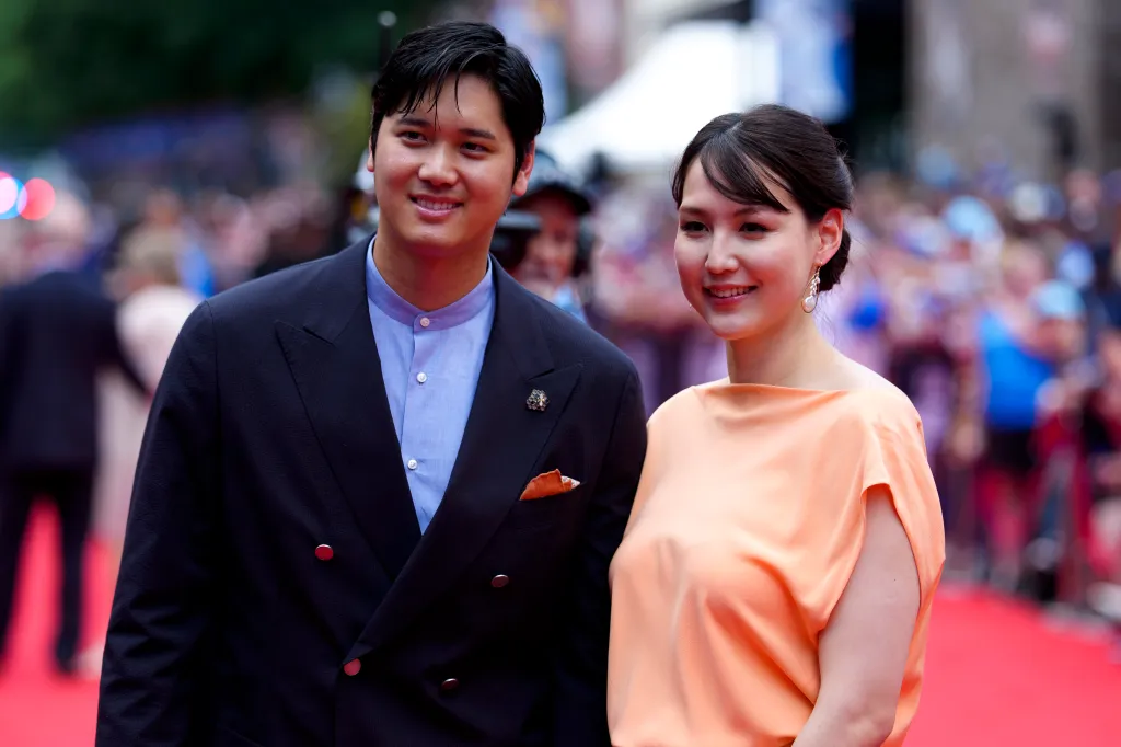 Shohei Ohtani and his wife Mamiko Tanaka posing on a red carpet.