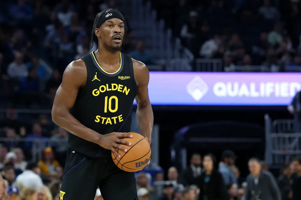 Jimmy Butler, wearing a Golden State Warriors jersey with number 10, holding a basketball during a game.