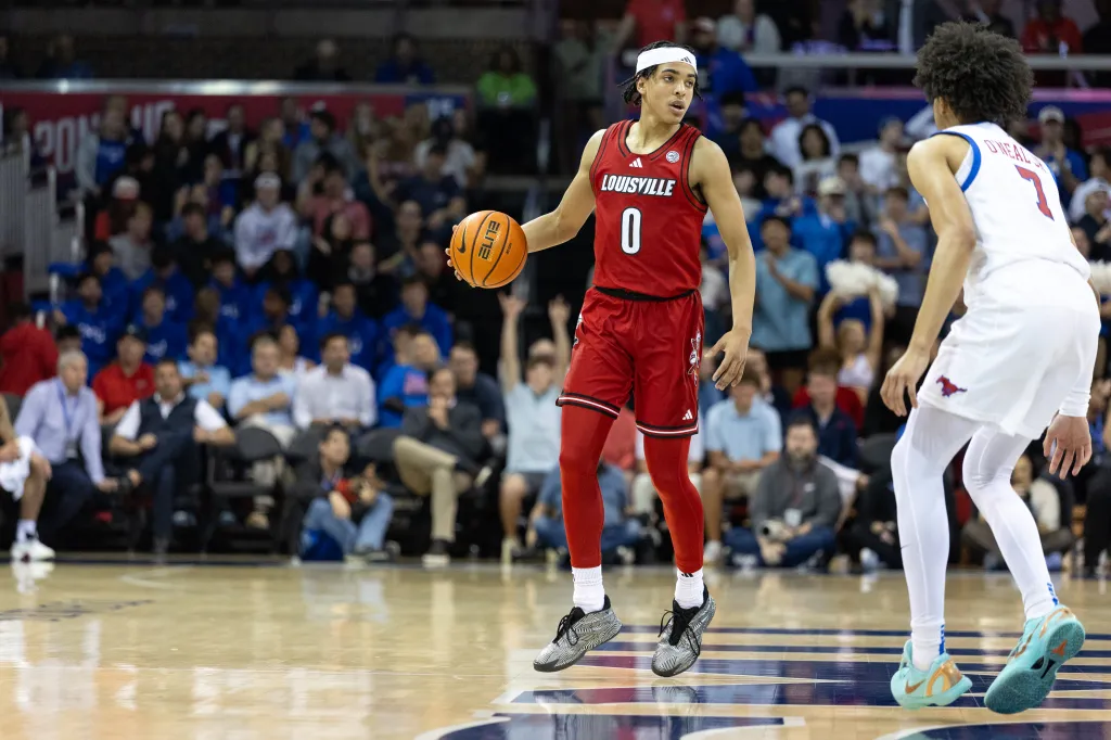 A Louisville player in a red jersey and a SMU player in a white jersey on the basketball court.