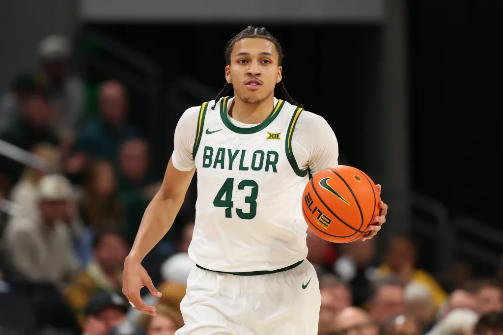 A basketball player in a white and green Baylor jersey with the number 43 dribbles a basketball.