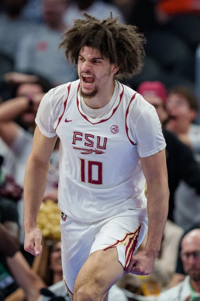 A Florida State basketball player in a white uniform with number 10, mouth open in a roar or shout.