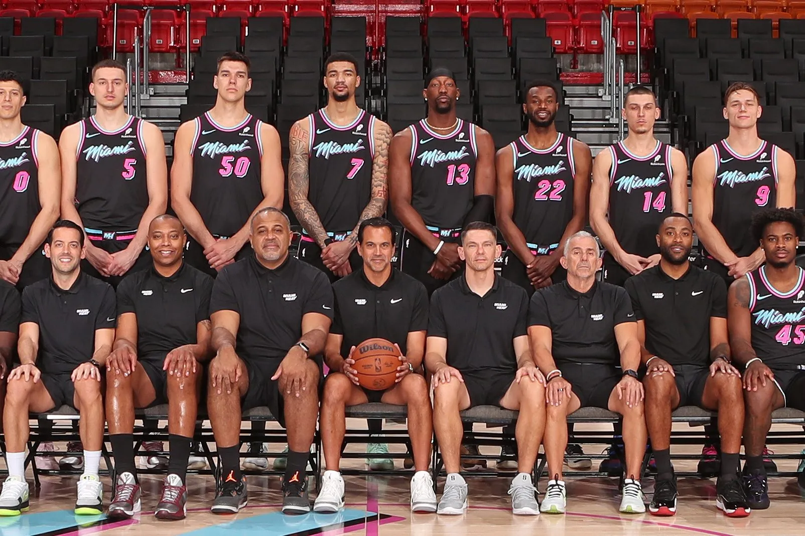 A group photo of the Miami Heat basketball team with players and staff in an arena.