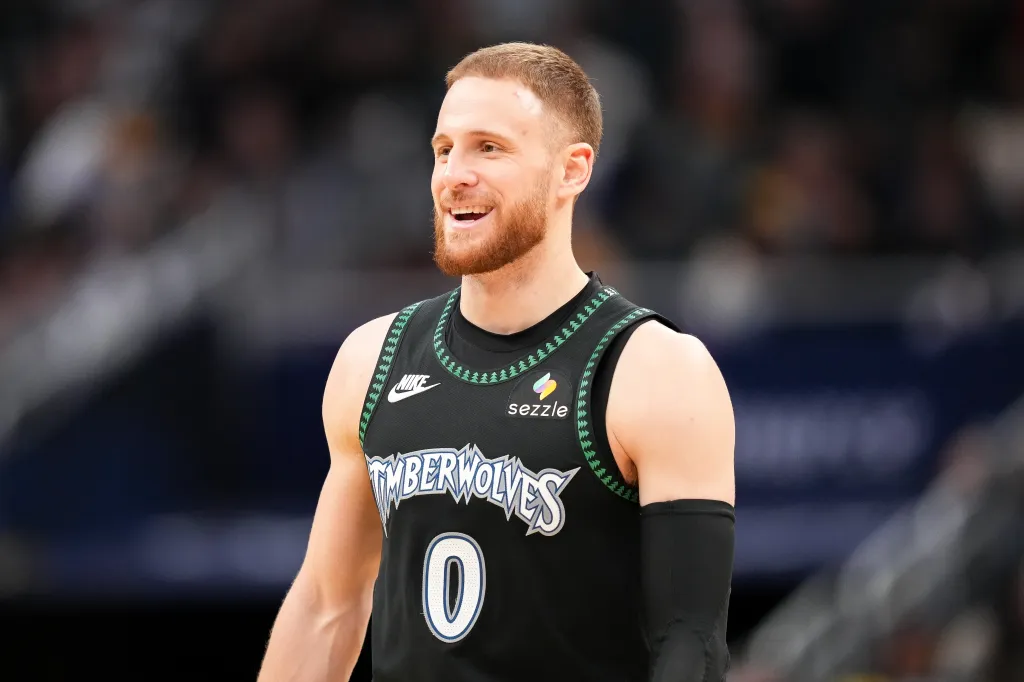 Minnesota Timberwolves player sporting a red beard, smiling while wearing a black jersey with "Timberwolves" across the chest.