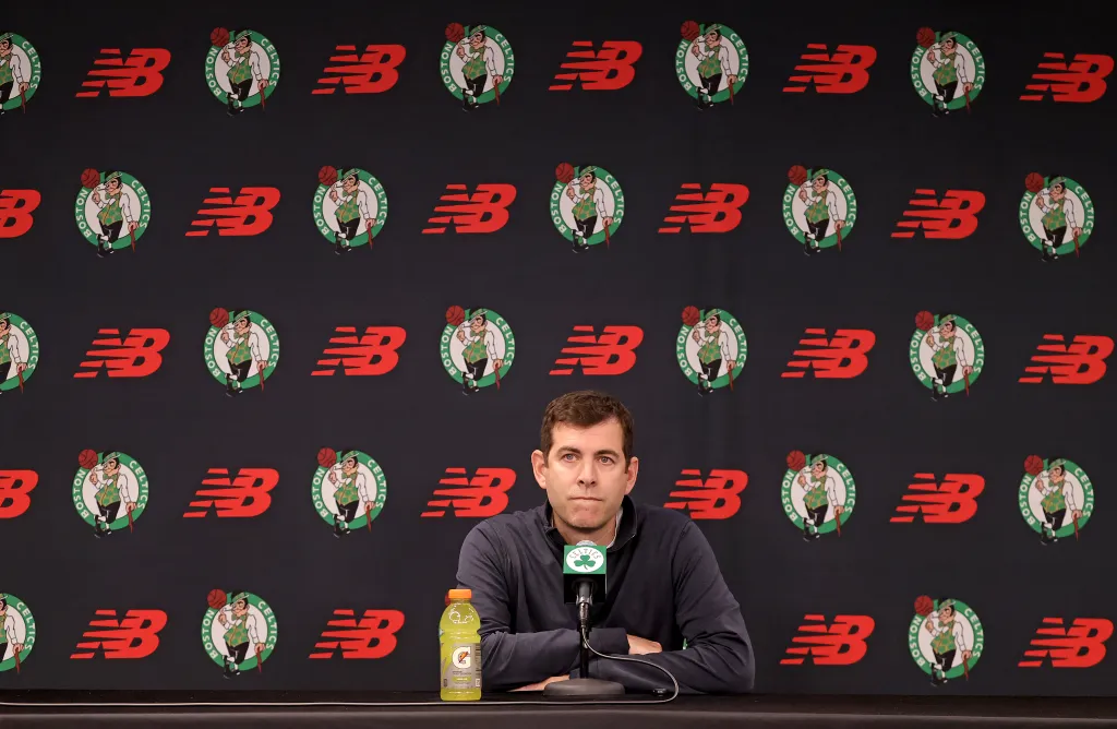 Brad Stevens at a press conference in front of a backdrop of Boston Celtics and New Balance logos.